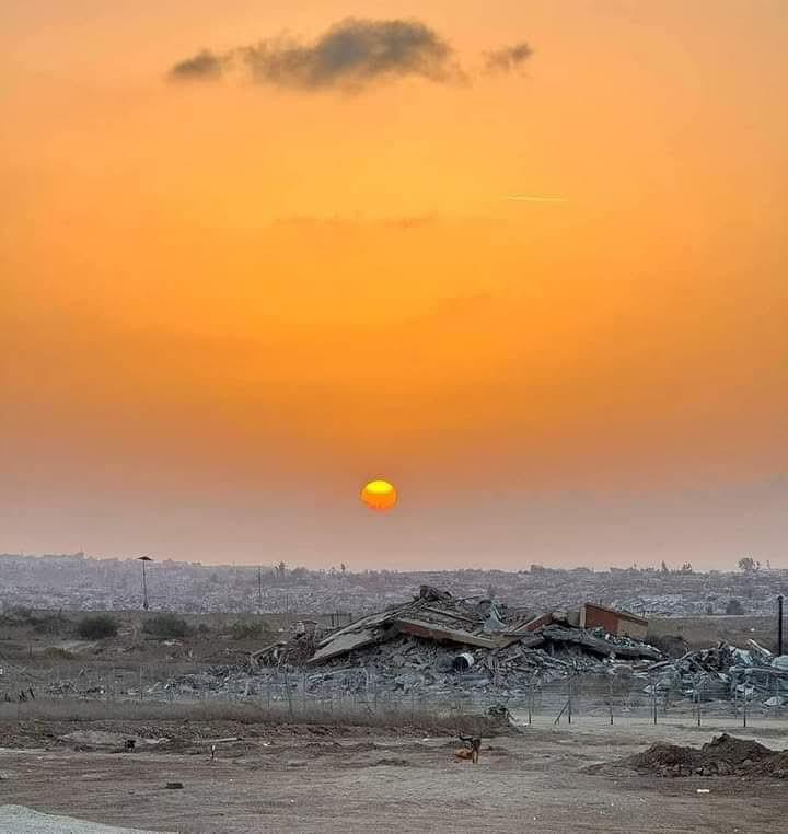 Sunset over a pile of concrete rubble and destroyed buildings in Gaza.